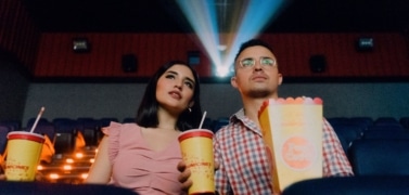 A young couple is watching book adaptation on screen in a cinema