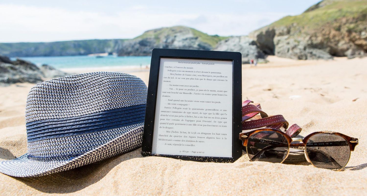 EReader on summer beach with sunglasses and summer hat